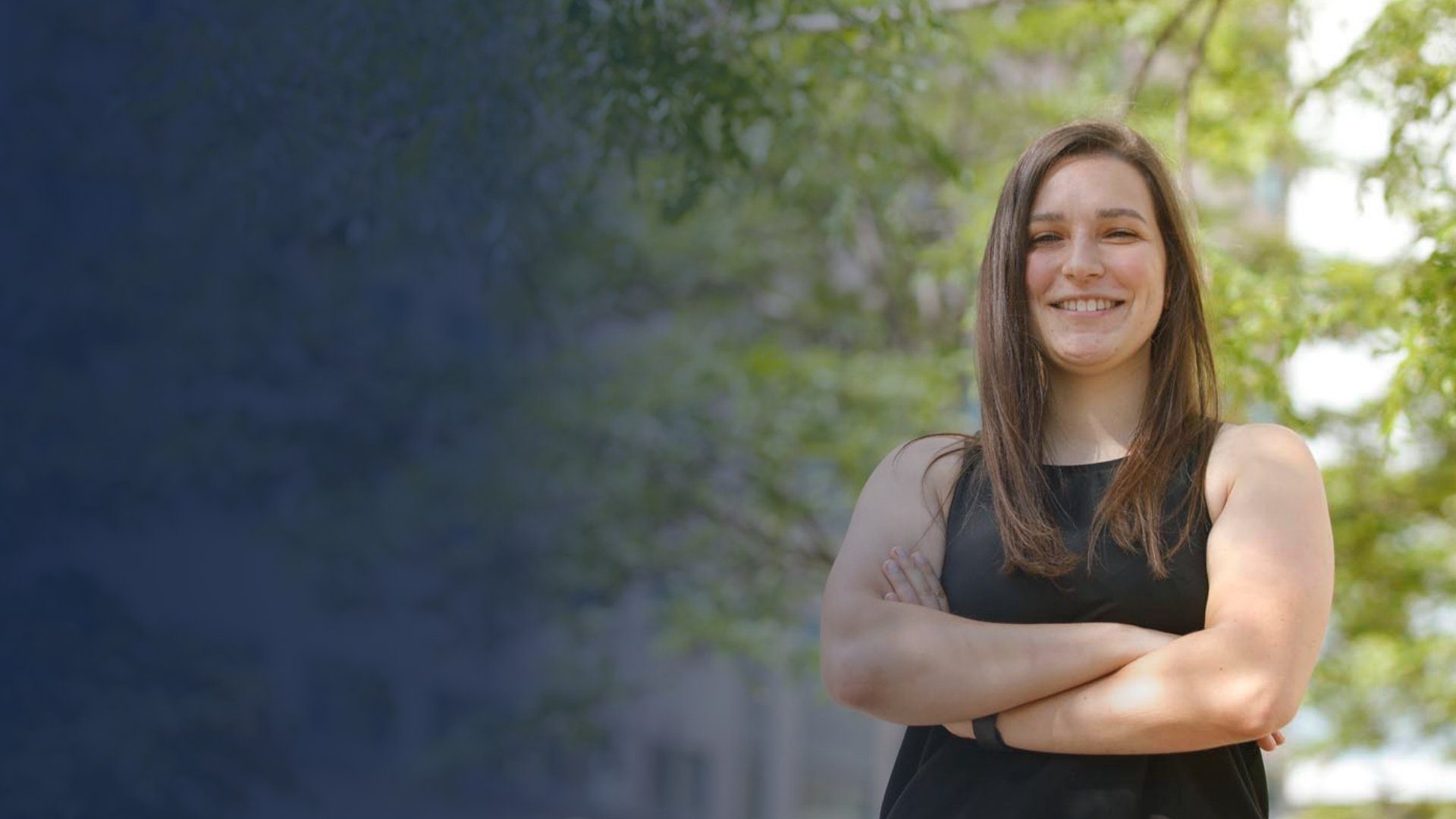 Woman with arms crossed and smiling outside