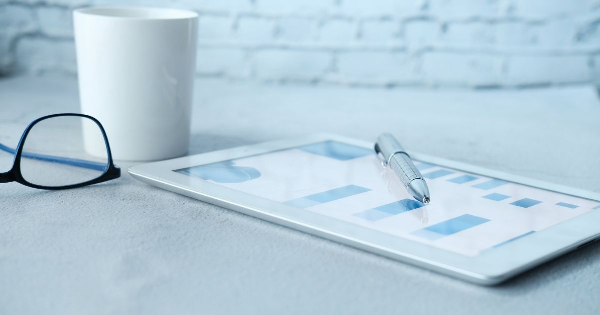 image of white surface with tablet, glasses, pen, and coffee mug to signify It's time to clean up your chart of accounts