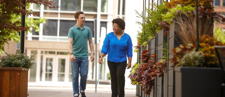 Two people walking together on sidewalk